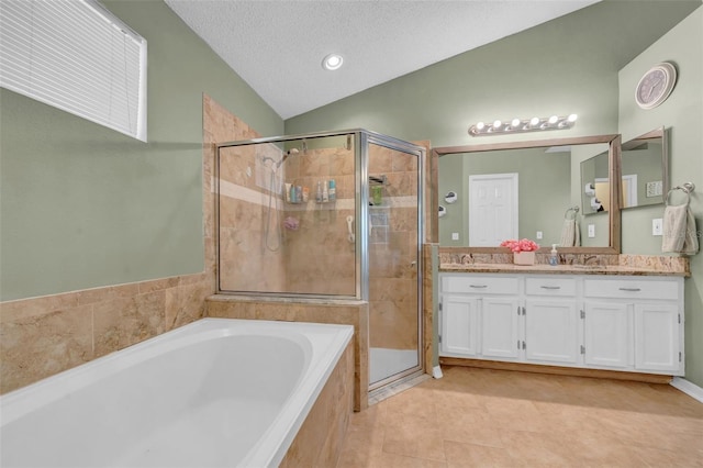 bathroom with double vanity, a stall shower, a garden tub, vaulted ceiling, and a textured ceiling