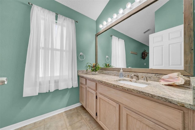 bathroom with lofted ceiling, vanity, baseboards, visible vents, and tile patterned floors