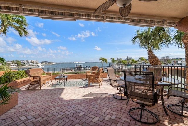 view of patio / terrace featuring outdoor dining space, a water view, and a ceiling fan