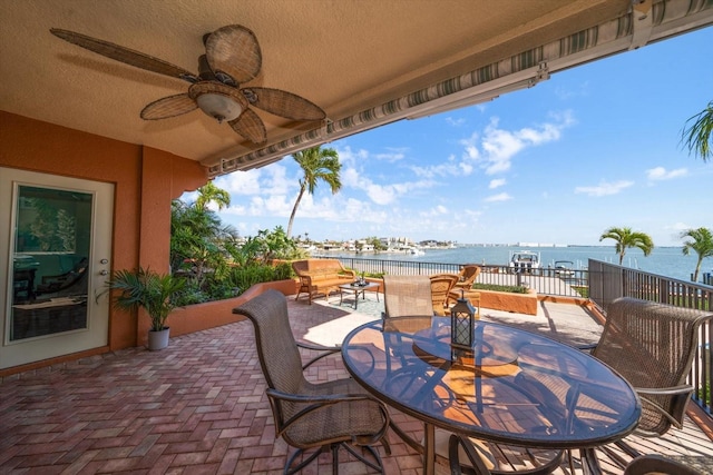 view of patio / terrace featuring a water view, a ceiling fan, and outdoor dining space