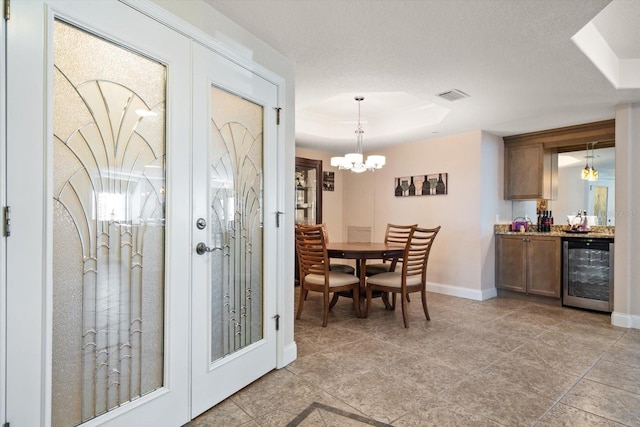 dining area featuring beverage cooler, baseboards, visible vents, a tray ceiling, and a bar