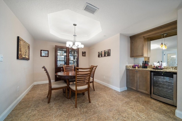 dining area featuring beverage cooler, a dry bar, visible vents, baseboards, and a tray ceiling