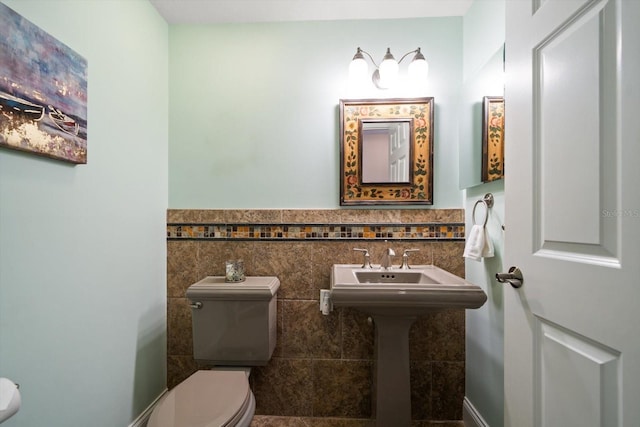 bathroom featuring wainscoting, a sink, toilet, and tile walls