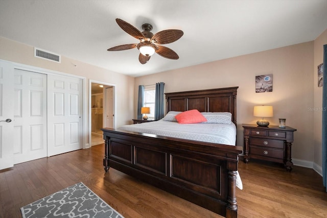 bedroom featuring dark wood-style floors, a closet, visible vents, ensuite bathroom, and a ceiling fan