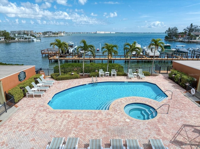 community pool with a water view, fence, and a community hot tub