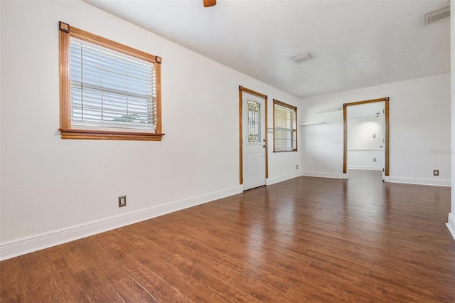 unfurnished room with a ceiling fan, baseboards, and dark wood-type flooring