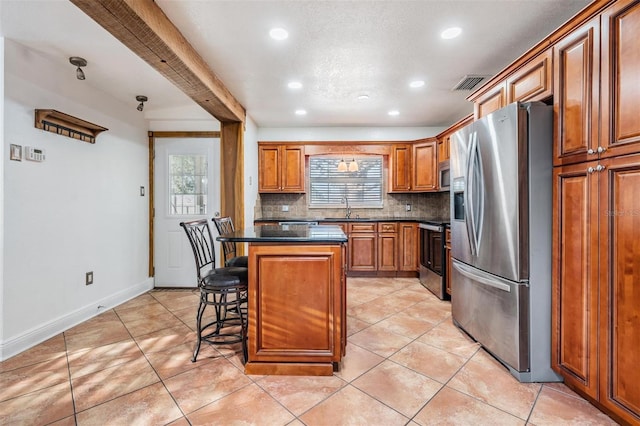 kitchen with stainless steel appliances, a breakfast bar, a sink, a kitchen island, and dark countertops