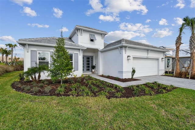 view of front of home with an attached garage, stucco siding, decorative driveway, and a front yard