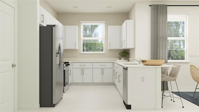 kitchen with a kitchen bar, appliances with stainless steel finishes, white cabinets, and light countertops