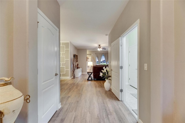 corridor with light wood-type flooring and baseboards