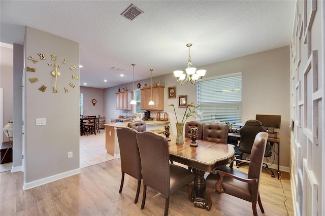 dining area featuring light wood-type flooring, visible vents, a notable chandelier, and a textured ceiling