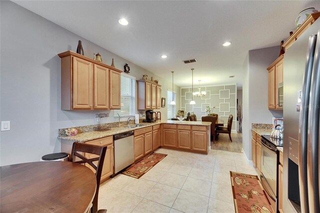 kitchen featuring light stone counters, stainless steel appliances, visible vents, decorative light fixtures, and an inviting chandelier