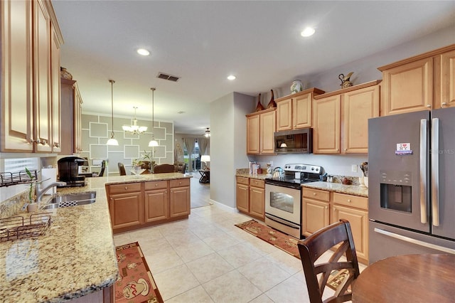 kitchen featuring stainless steel appliances, hanging light fixtures, a sink, and light brown cabinetry