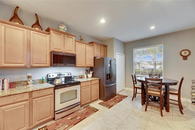 kitchen featuring baseboards, light stone counters, stainless steel appliances, light brown cabinets, and recessed lighting