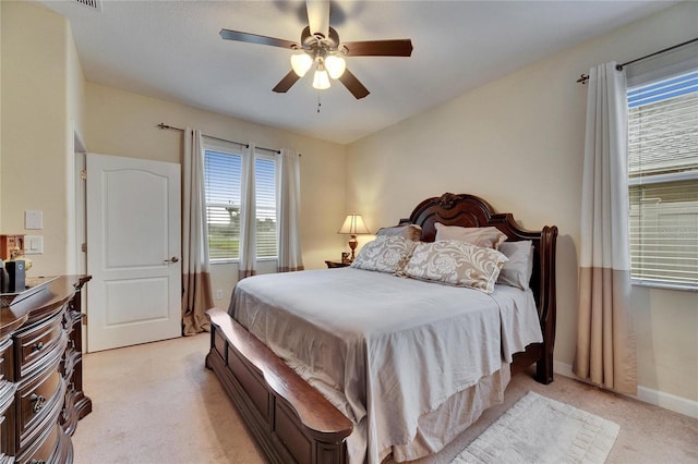 bedroom featuring light carpet, a ceiling fan, and baseboards