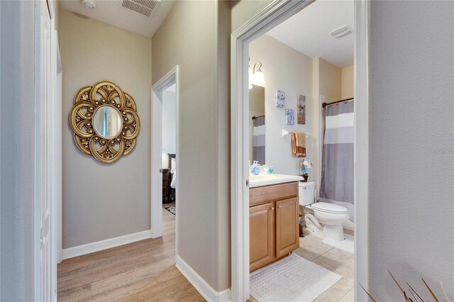 corridor featuring light wood-style floors, visible vents, and baseboards