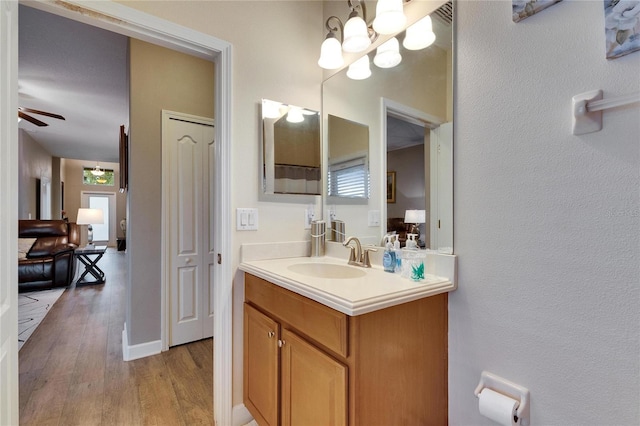 bathroom featuring ceiling fan with notable chandelier, wood finished floors, vanity, and baseboards