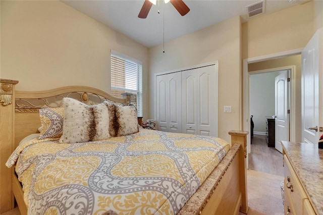 bedroom with light wood finished floors, ceiling fan, visible vents, and a closet