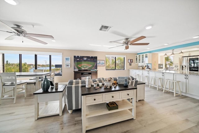 living room featuring visible vents, a ceiling fan, light wood-style flooring, and crown molding