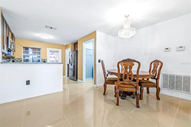 dining room featuring baseboards, visible vents, and an inviting chandelier