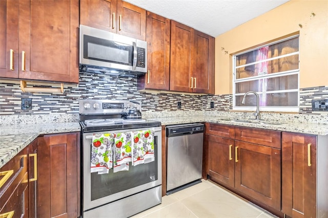 kitchen featuring tasteful backsplash, light stone counters, stainless steel appliances, and a sink