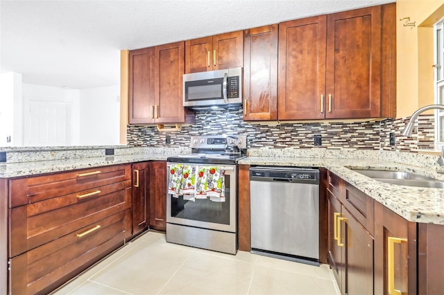 kitchen featuring light stone countertops, backsplash, stainless steel appliances, and a sink