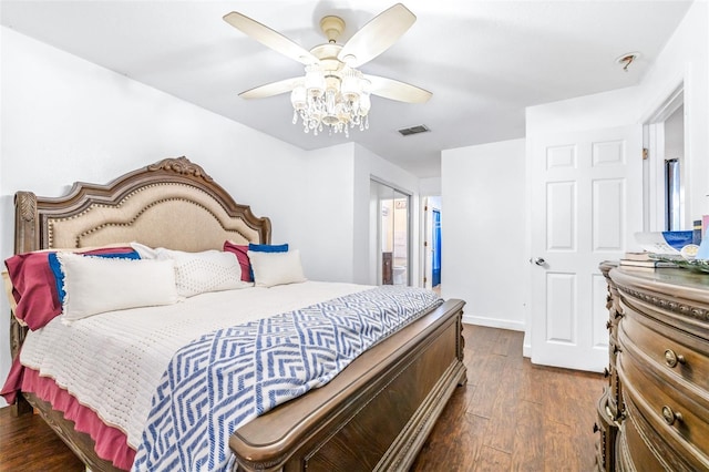 bedroom featuring ceiling fan, ensuite bathroom, visible vents, baseboards, and dark wood-style floors