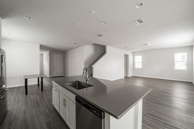 kitchen featuring stainless steel appliances, dark countertops, open floor plan, white cabinets, and a sink