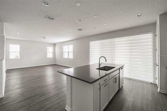 kitchen with a center island with sink, dark countertops, visible vents, white cabinets, and dishwasher