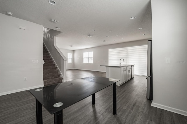 recreation room with a textured ceiling, baseboards, and dark wood-style flooring