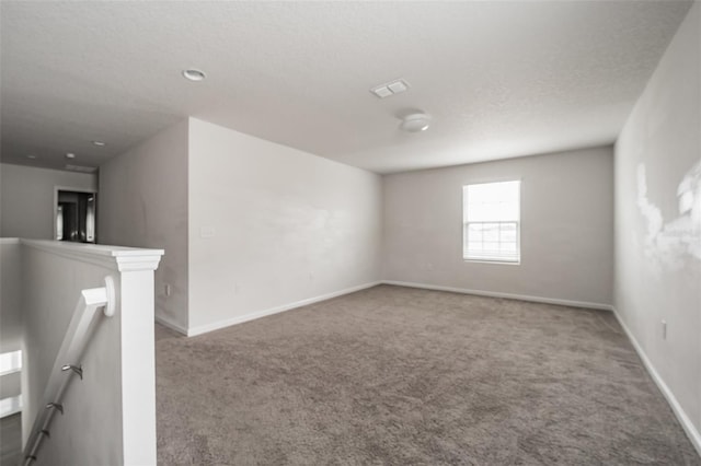 spare room featuring visible vents, carpet flooring, a textured ceiling, and baseboards