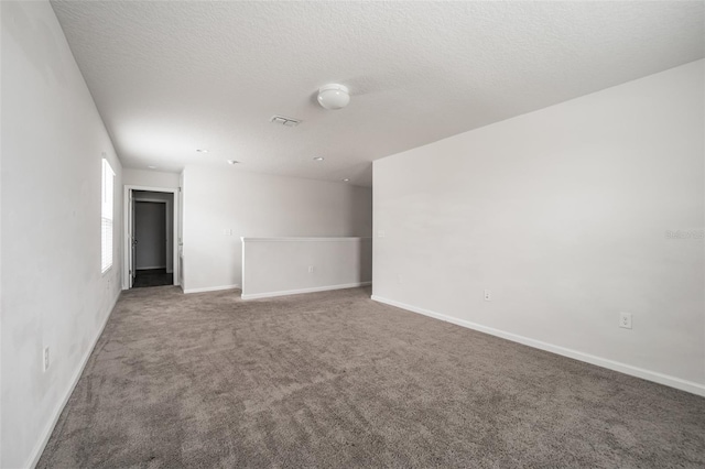 spare room with carpet floors, visible vents, baseboards, and a textured ceiling