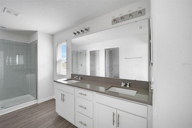 bathroom featuring a stall shower, visible vents, a sink, and wood finished floors