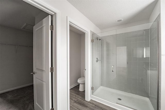 full bathroom with a stall shower, baseboards, a textured ceiling, and toilet