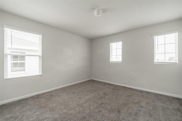 carpeted empty room featuring baseboards and a textured ceiling