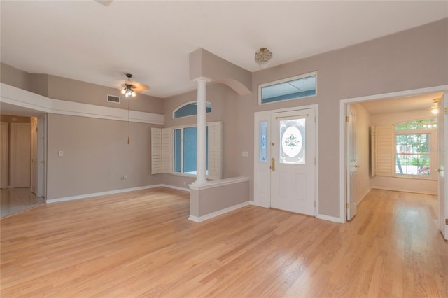 foyer featuring light wood finished floors, visible vents, plenty of natural light, and ornate columns