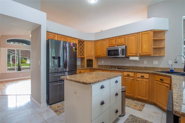 kitchen featuring a sink, light stone counters, a center island, stainless steel appliances, and brown cabinetry