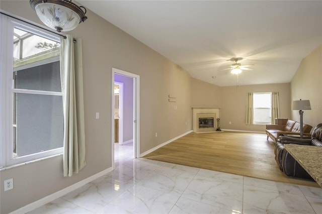 living room with a glass covered fireplace, baseboards, marble finish floor, and ceiling fan