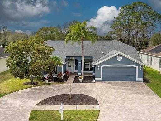 view of front of property featuring a front lawn, decorative driveway, and a garage