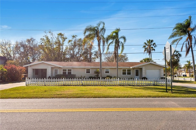 ranch-style home featuring a garage, driveway, a fenced front yard, and a front lawn