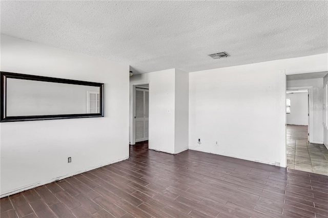 unfurnished room with a textured ceiling, visible vents, and wood tiled floor