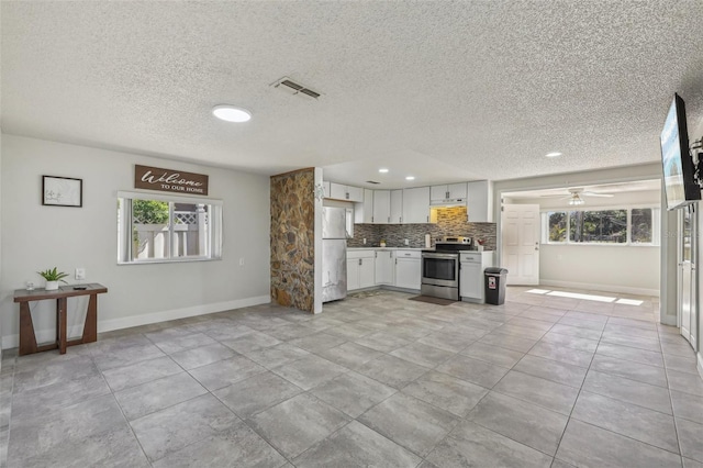 kitchen with visible vents, white cabinets, decorative backsplash, open floor plan, and stainless steel appliances