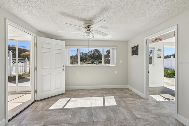 foyer with baseboards, a textured ceiling, a ceiling fan, and a wealth of natural light