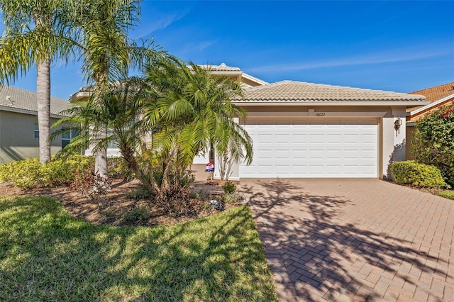 view of front of home with a garage, a tile roof, decorative driveway, and stucco siding