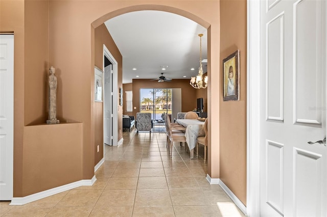 hall featuring light tile patterned floors, recessed lighting, arched walkways, and baseboards