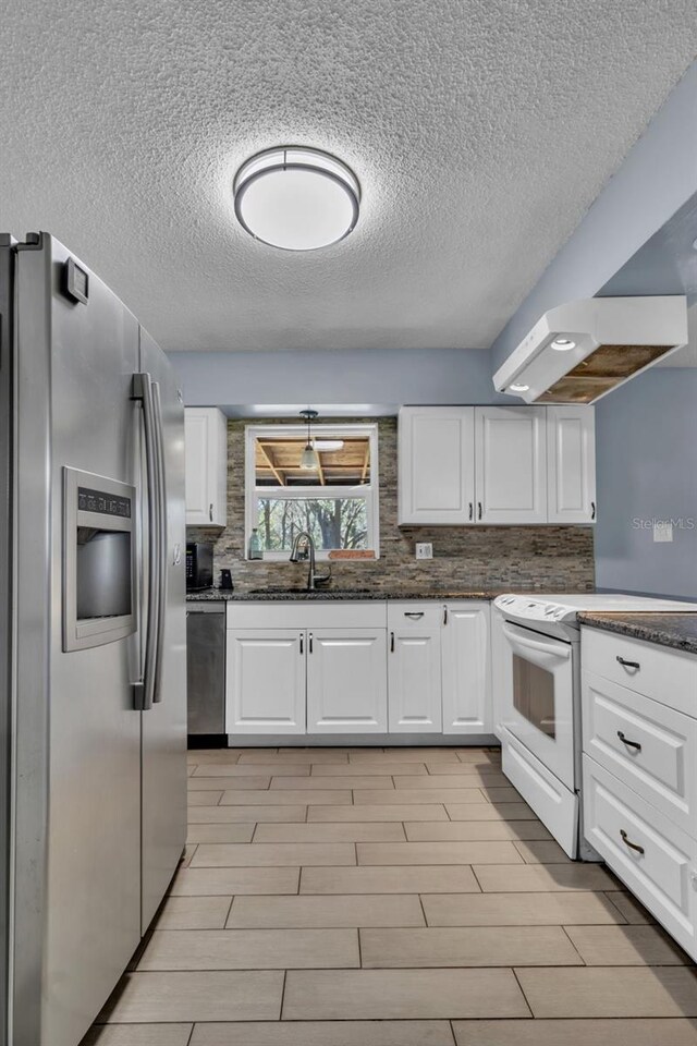 kitchen with dark countertops, white cabinets, stainless steel appliances, and a sink