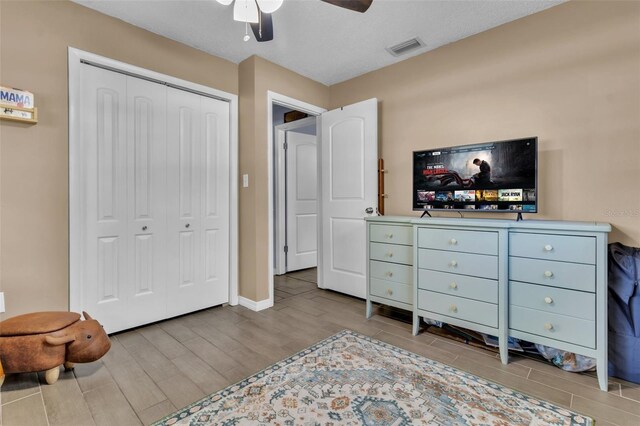 bedroom featuring a ceiling fan, baseboards, visible vents, a closet, and wood tiled floor