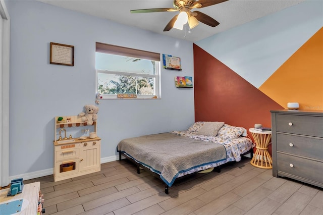 bedroom with ceiling fan, baseboards, and wood finish floors