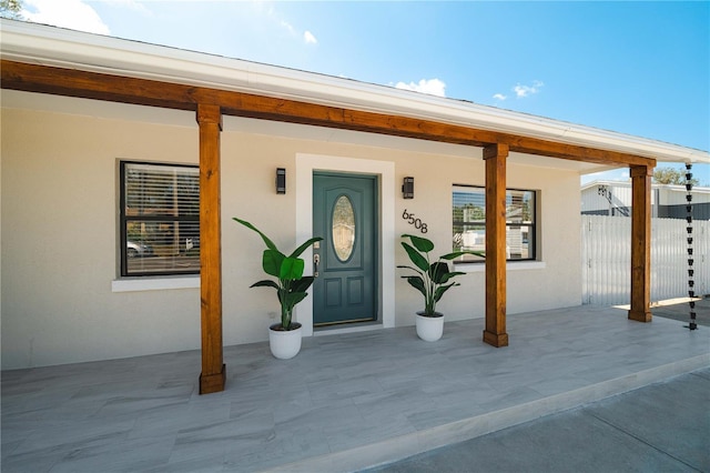 doorway to property with fence and stucco siding