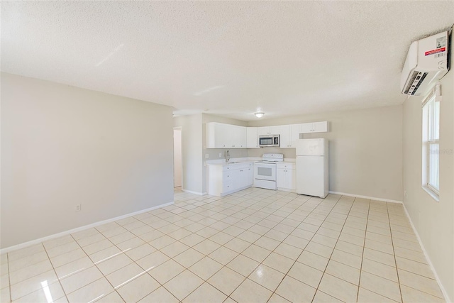 kitchen with white appliances, white cabinets, a wall mounted air conditioner, light countertops, and a sink